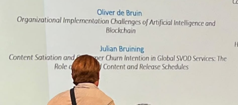 Oliver at his VU graduation, with his name and AI–blockchain thesis title on the presentation screen